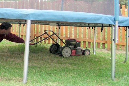 mowing grass under a trampoline